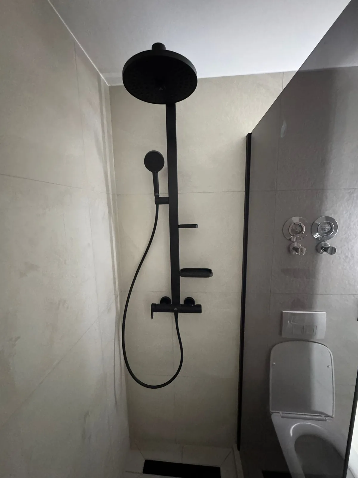 Matte-black rainfall walk-in shower in a renovated bathroom