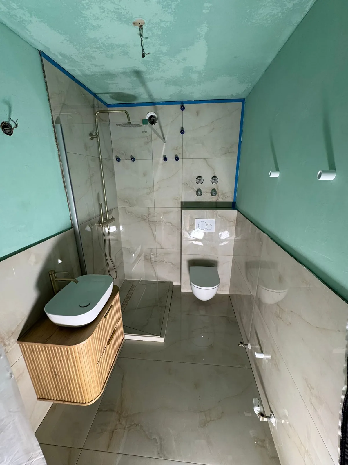 Marble-look bathroom with brushed-gold shower and fluted wood vanity