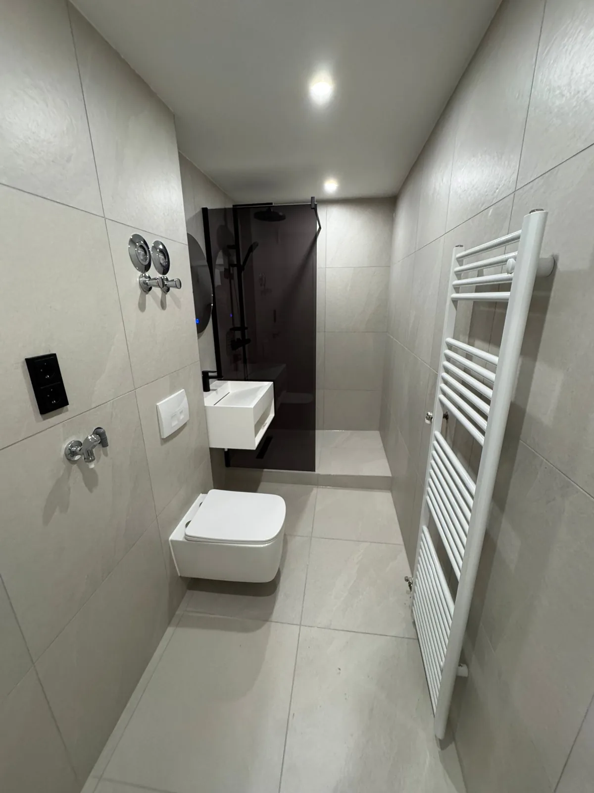 Grey walk-in shower bathroom with black fittings and glass screen