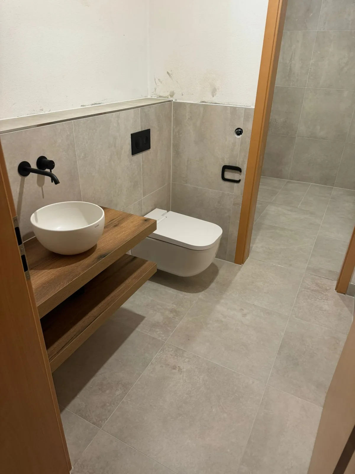 Round basin on an oak shelf with matte-black taps