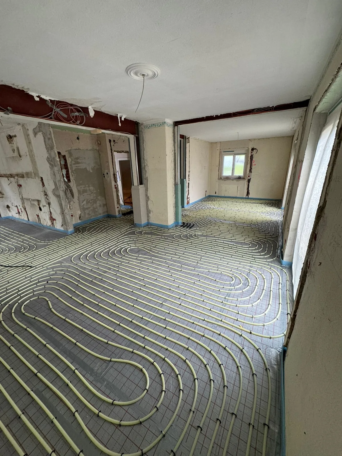 Underfloor heating loops laid across a stripped room